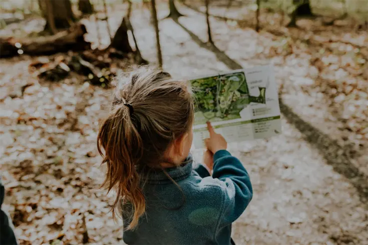 A young girl outdoors looking at an information pamphlet
