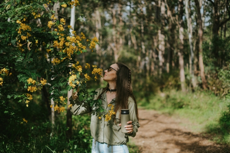Woman smelling a flower while on a bushwalk